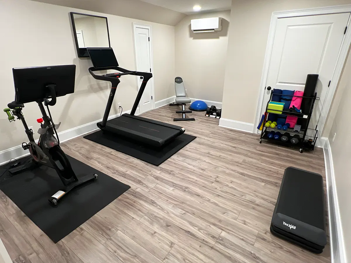 Home gym setup with treadmill, bike, and equipment in a finished attic space with vinyl plank flooring.