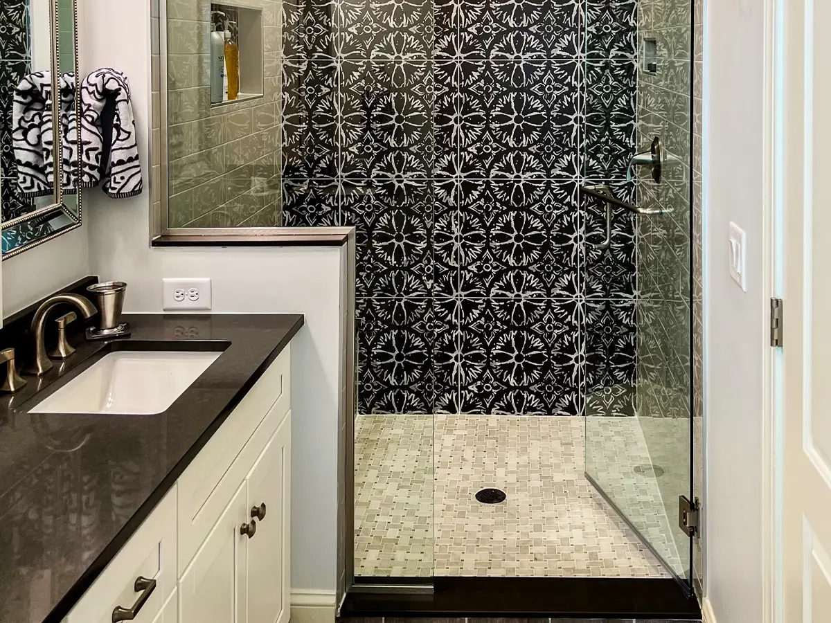 Stylish black-and-white bathroom with patterned shower tiles and modern fixtures.