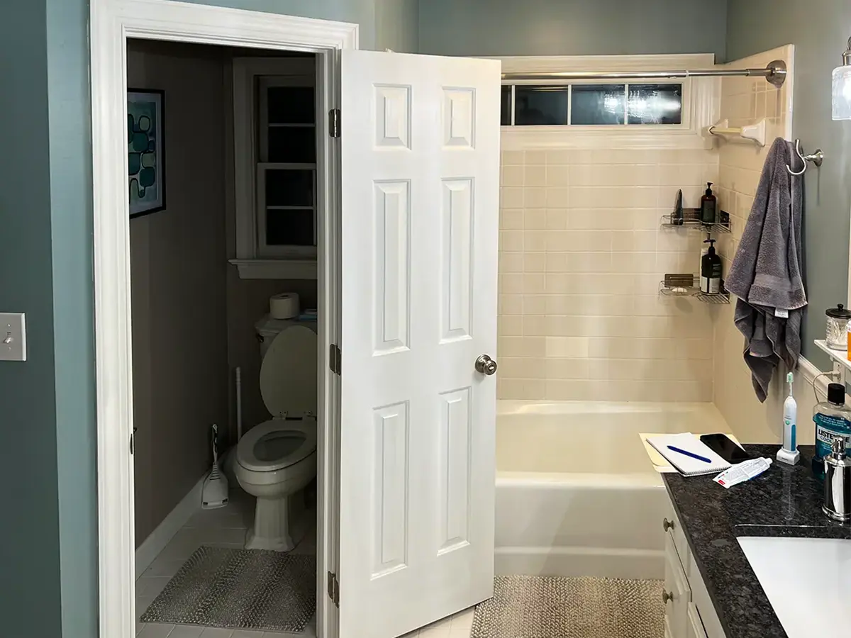 Pre-renovation bathroom with a dated tub and tiled walls.