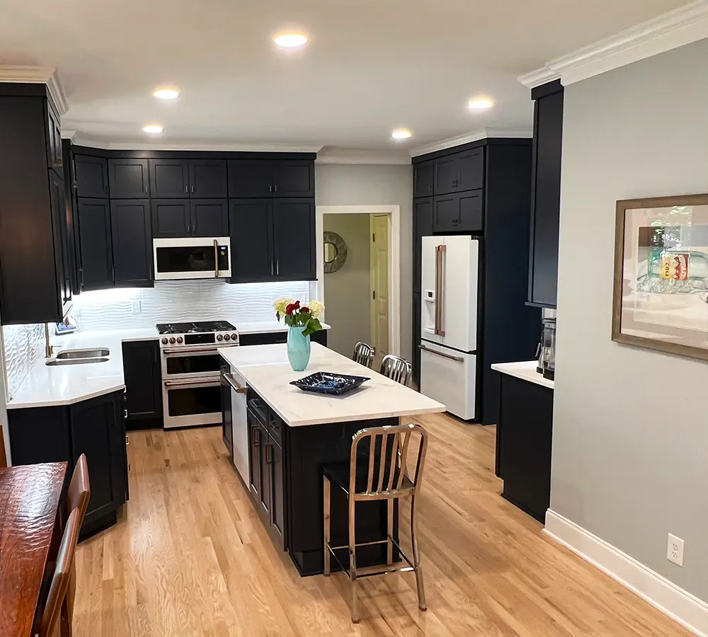 Stylish black cabinets with stainless steel appliances in a sleek and contemporary kitchen layout.