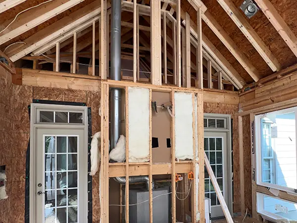 Interior framing of a sunroom under construction with exposed beams and insulation.