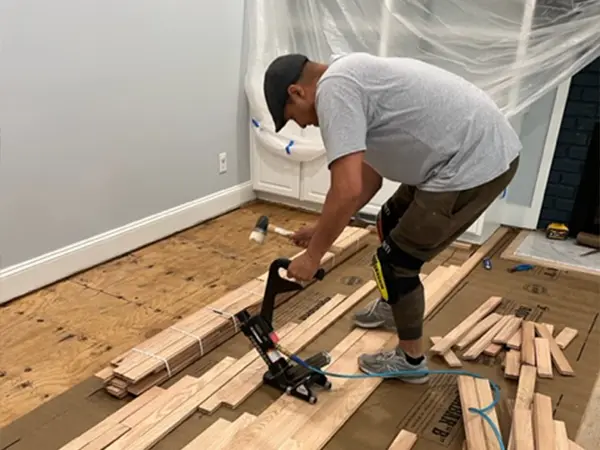 A contractor installing hardwood flooring during a kitchen remodeling project.