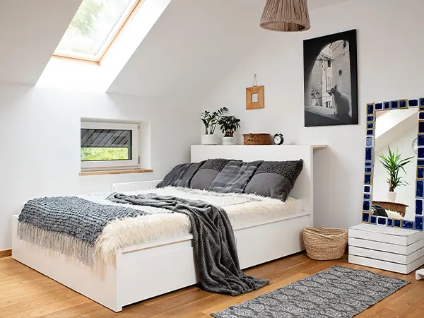 Bright attic bedroom with cozy furnishings, skylight, and modern decor after attic renovation project.