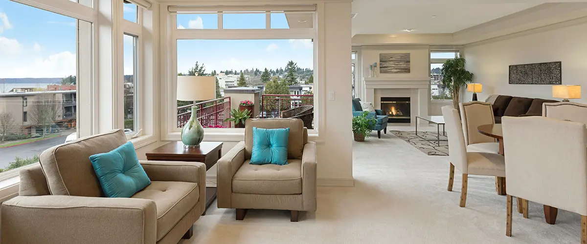 Bright living room with panoramic windows, beige furniture, and modern fireplace showcasing luxury apartment design.