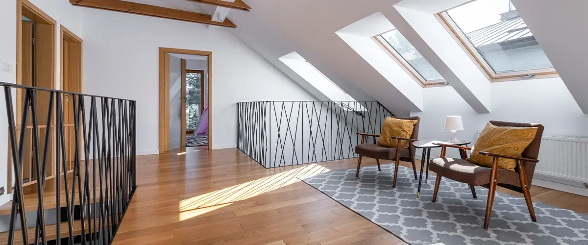 Modern attic sitting area with skylight windows, wooden beams, cozy armchairs, and hardwood flooring - stylish loft interior.