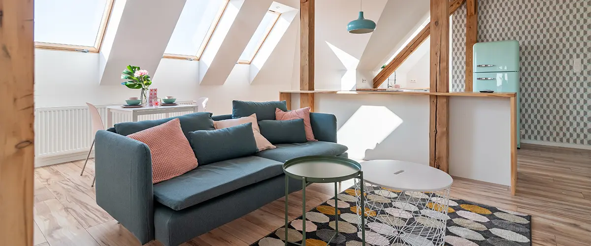 Stylish attic living space featuring exposed wooden beams, vibrant furniture, and abundant natural lighting through skylights.