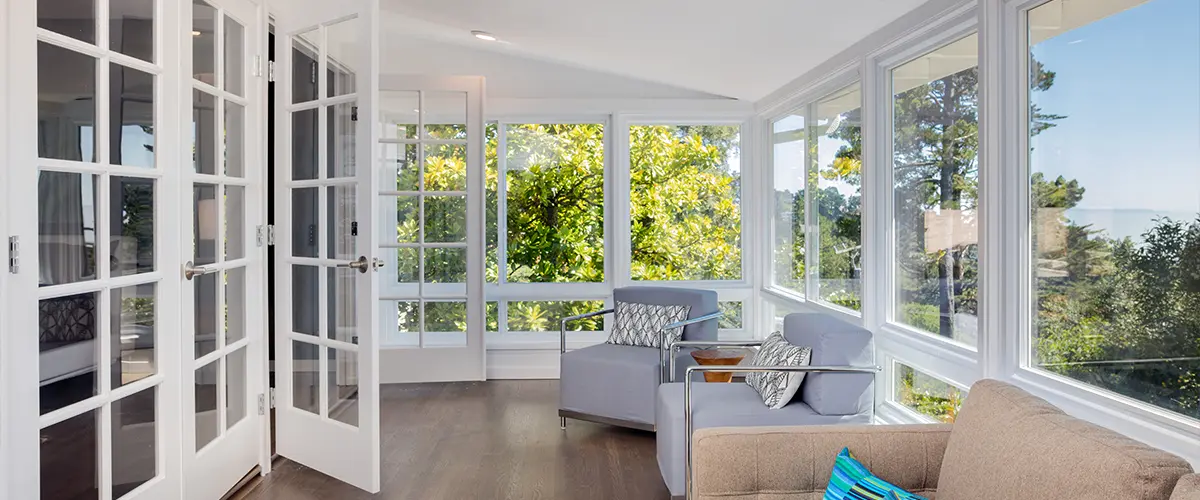 Sunlit living area with French doors, large windows, modern furniture, and garden view - home interior design inspiration.