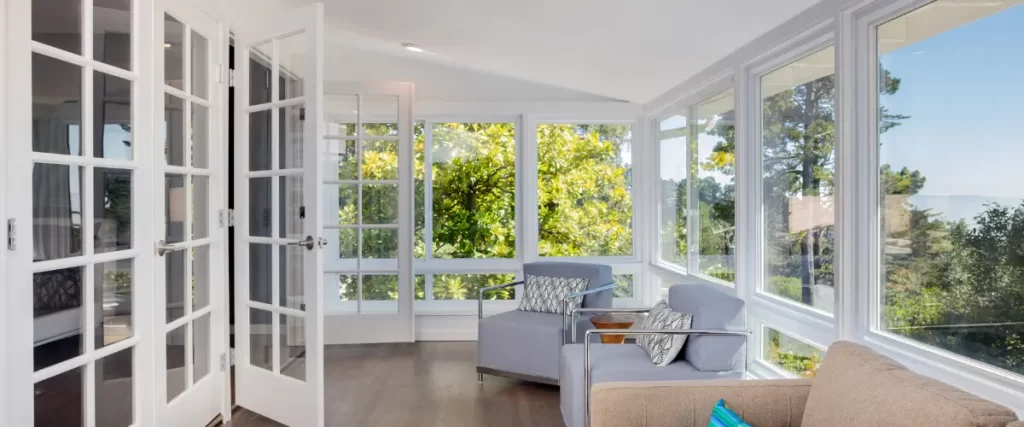 Bright and airy sunroom with wraparound windows and comfortable chairs