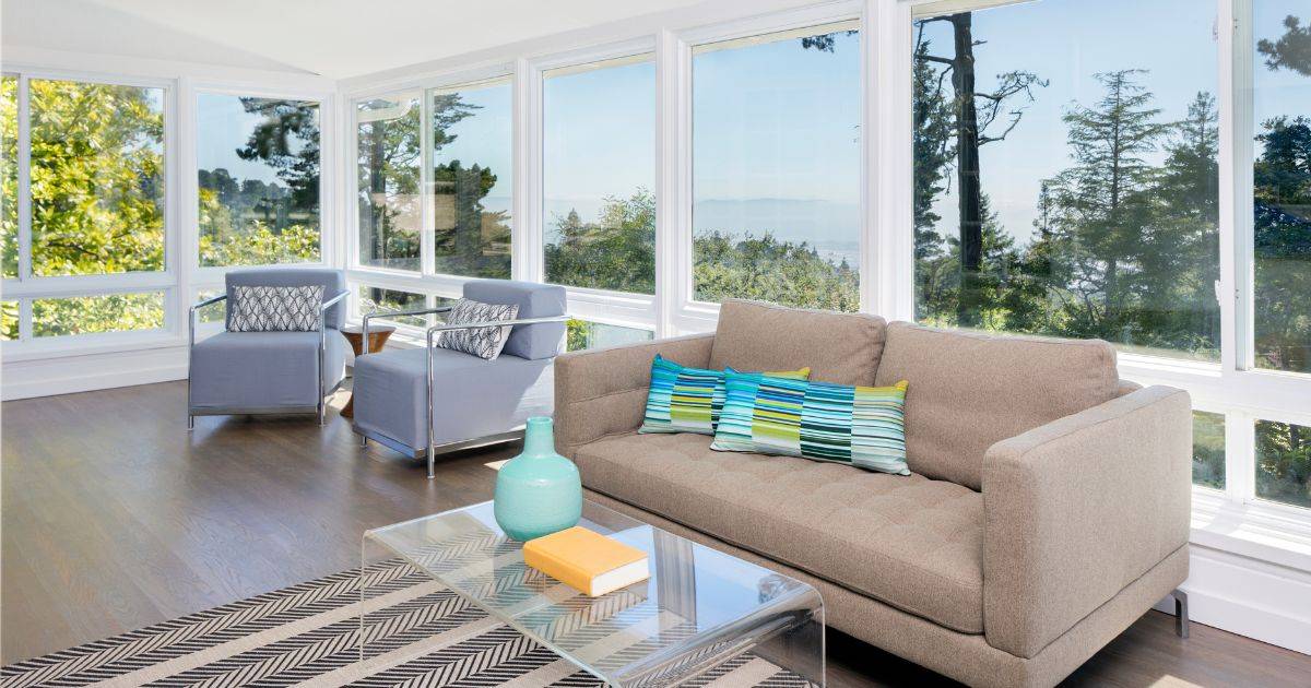 Modern sunroom with beige sofa, colorful pillows, and large windows