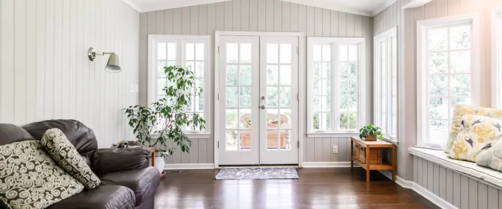 Bright sunroom with double French doors and indoor plant