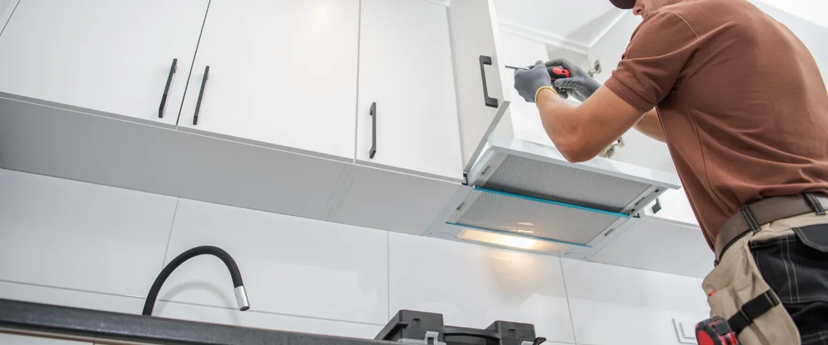 Contractor installing range hood in a white kitchen