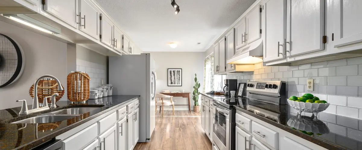 Galley kitchen with white cabinets and black countertops